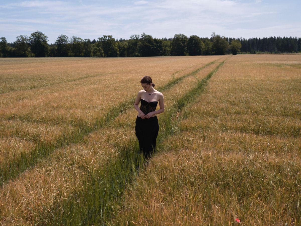 Frau in schwarzem Kleid läuft durch ein Feldweg im Getreide – Editorial Styling & Make-up