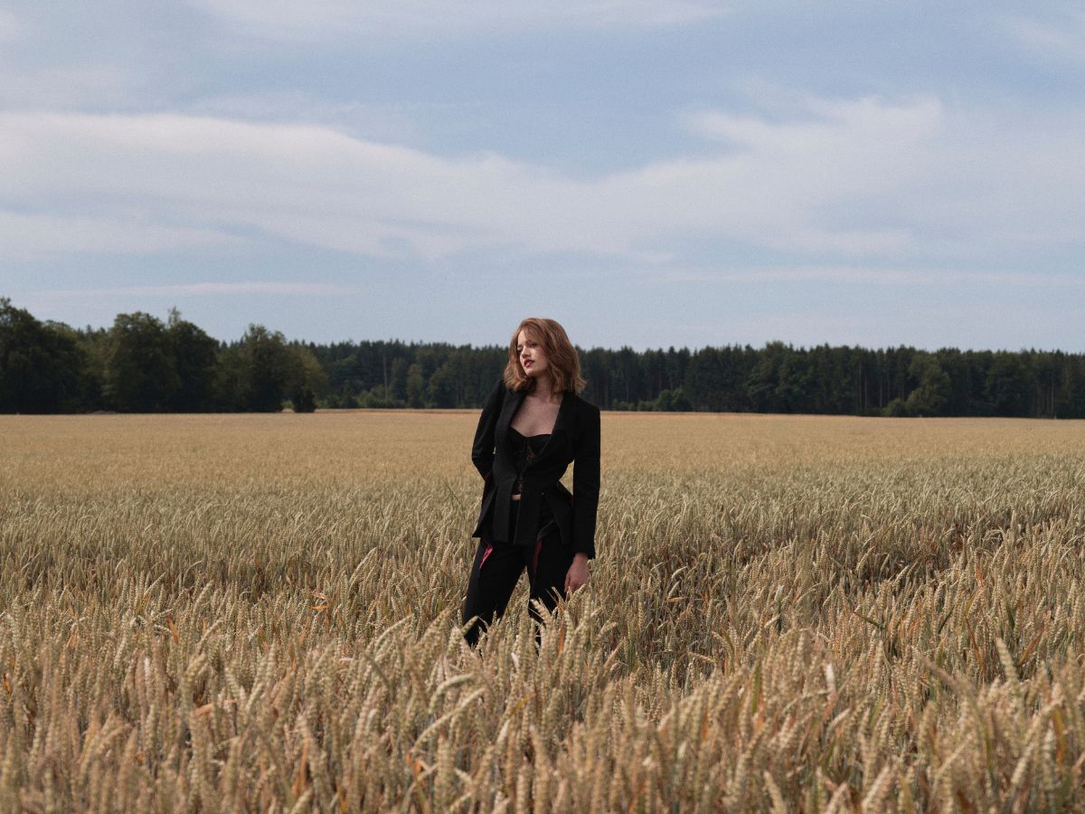Frau im schwarzen Outfit steht im Kornfeld – Styling und Make-up von Julia Ebert für FOGS Green Style Magazin.
