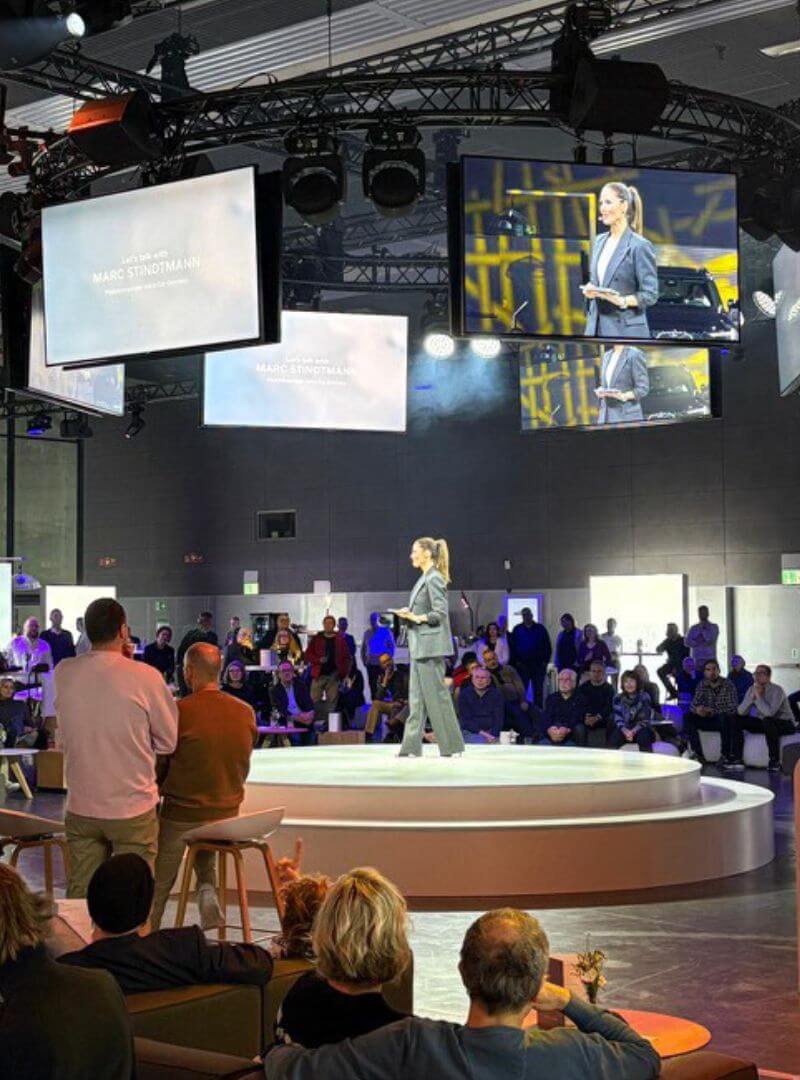 TV-Event-Gallery-Hochformat-Volvo-Moderatorin Moderatorin auf der Volvo Roadshow in München auf der Bühne, Make-up und Frisur von Visagistin Julia Ebert